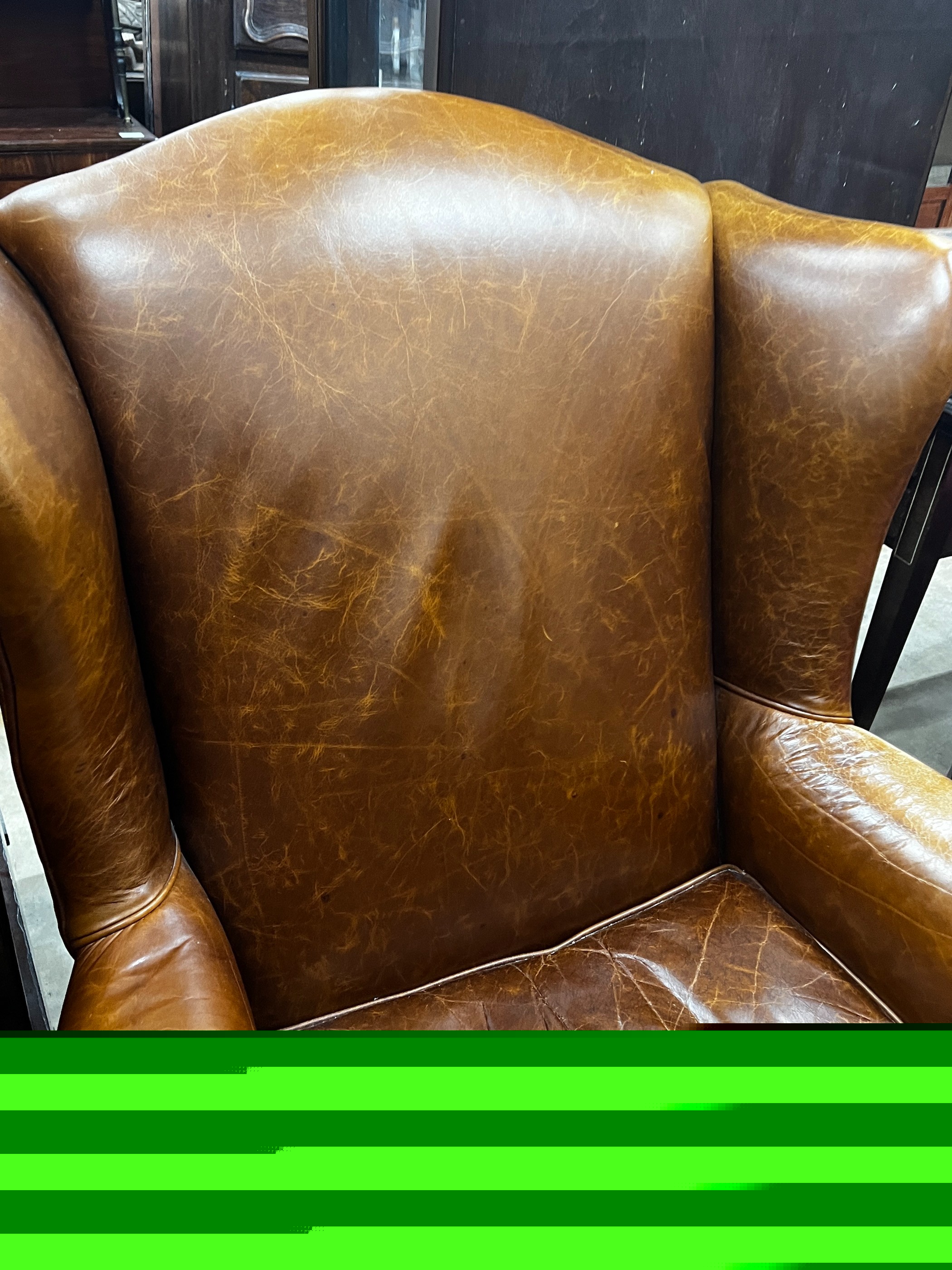 A Victorian style tan leather upholstered wingback armchair, width 78cm, depth 84cm, height 100cm